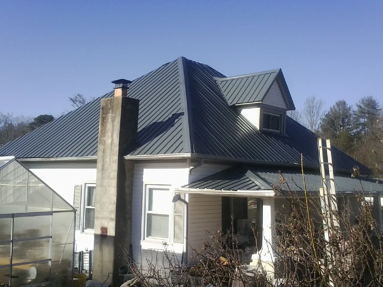 Dark blue standing seam metal roof on a white farmhouse with dormer — Slate & Tile Roof Repair by Roofing Brothers in Temple