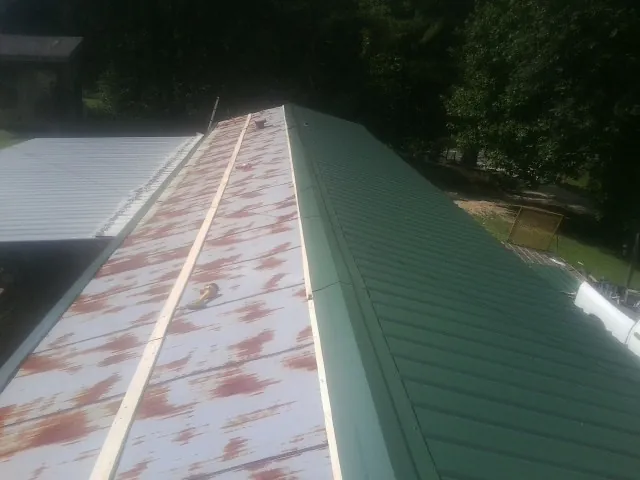 Old rusted panels beside newly installed green metal roofing — Wind Damage Roof Repair by Roofing Brothers in Temple
