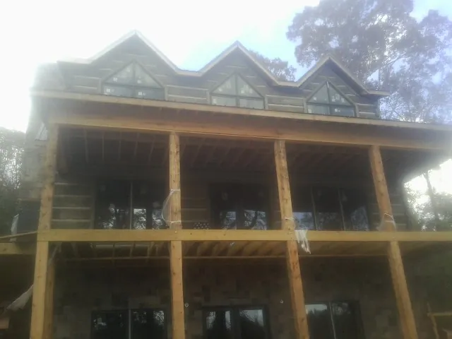Dormers and porch framing on a large log home under construction — Roof Coating work by our crew in Temple